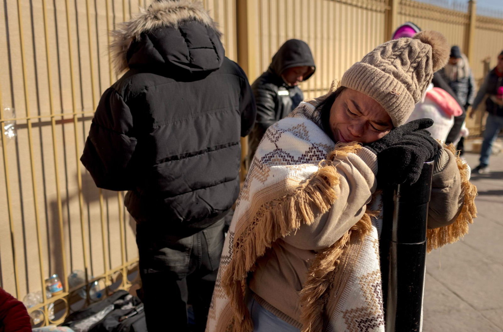 Grupo de migrantes en la frontera entre Estados Unidos y México esperando procesamiento, con agentes fronterizos supervisando, reflejando tensión y esperanza en medio de cambios legales recientes.