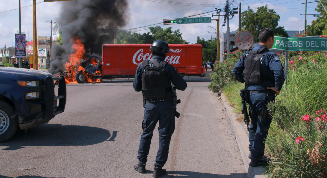 Agentes de la Guardia Nacional Mexicana con equipo táctico frente a un operativo en una calle de Nogales, Sonora, con la valla fronteriza entre México y Arizona visible al fondo, simbolizando la captura del sobrino de El Chapo y la cooperación binacional contra el narcotráfico.