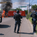Agentes de la Guardia Nacional Mexicana con equipo táctico frente a un operativo en una calle de Nogales, Sonora, con la valla fronteriza entre México y Arizona visible al fondo, simbolizando la captura del sobrino de El Chapo y la cooperación binacional contra el narcotráfico.