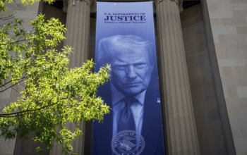 Vista exterior del edificio del Departamento de Justicia de los Estados Unidos en Washington D.C., con la bandera americana ondeando, representando la sede de la polémica decisión de crear el Fondo Anti-Weaponización de $1,800 millones actualmente bloqueado por un tribunal federal.