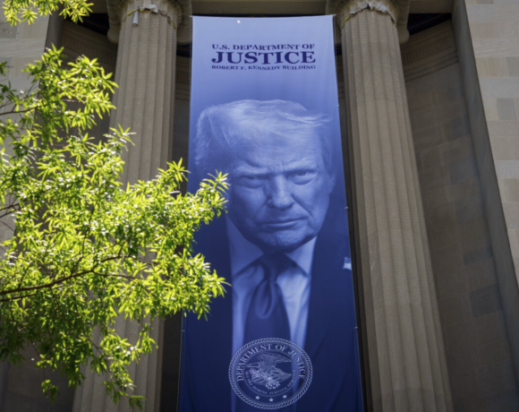 Vista exterior del edificio del Departamento de Justicia de los Estados Unidos en Washington D.C., con la bandera americana ondeando, representando la sede de la polémica decisión de crear el Fondo Anti-Weaponización de $1,800 millones actualmente bloqueado por un tribunal federal.