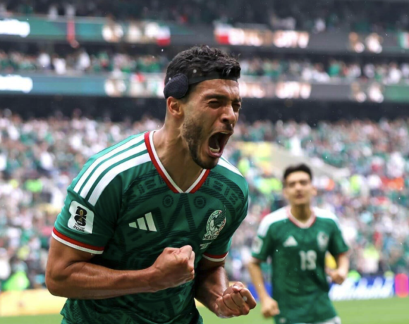 Julián Quiñones con el uniforme verde de la selección mexicana celebra el primer gol del Mundial 2026 ante una multitud eufórica en el Estadio Azteca de la Ciudad de México, con sus compañeros corriendo hacia él en señal de festejo.