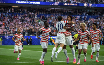 os jugadores de la selección masculina de Estados Unidos celebran uno de sus cuatro goles ante Paraguay en el SoFi Stadium de Inglewood, California, durante su debut en el Mundial 2026, rodeados de miles de aficionados con banderas americanas.